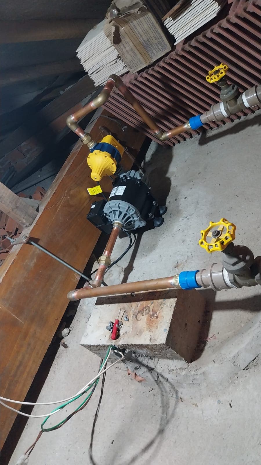 Pressurizador com controlador amarelo conectado à tubulação de cobre e a registros.